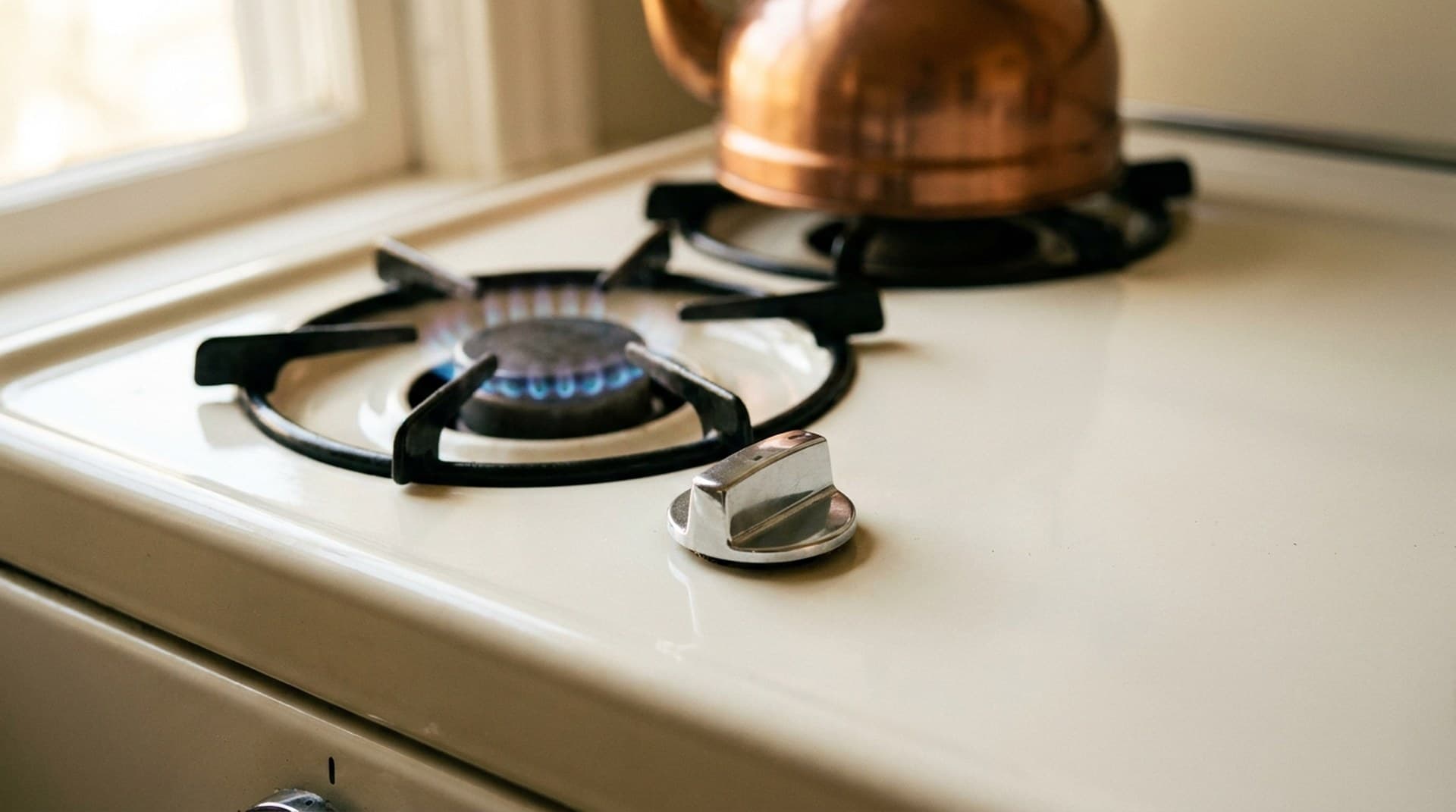 A cream enamel gas stove with one burner turned down to a tiny ring of blue flame and its chrome knob nearly at the lowest setting, a metaphor for Claude Opus 5.5 thinking that can be turned down but not off