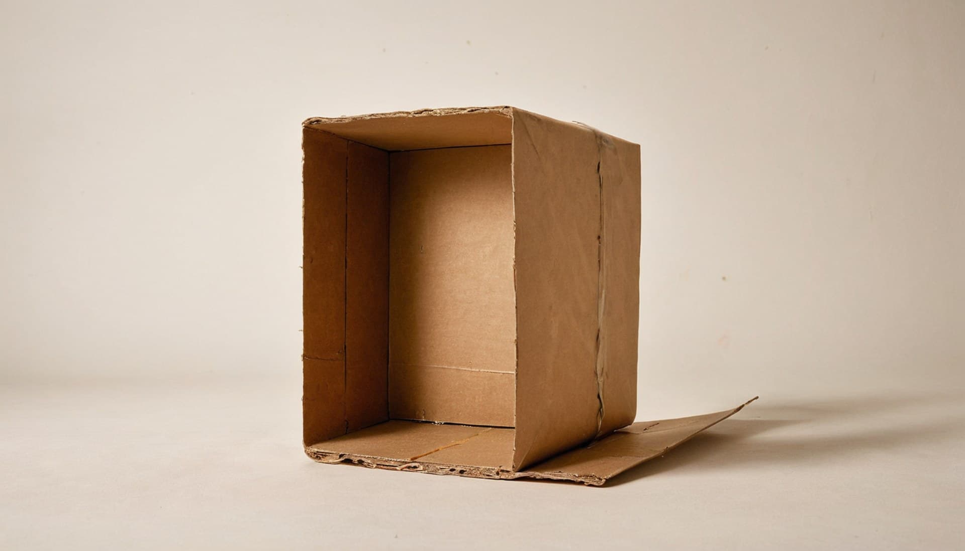 An opened and emptied kraft cardboard parcel on a plain studio surface, representing a trusted MCP server package that turned out to be compromised