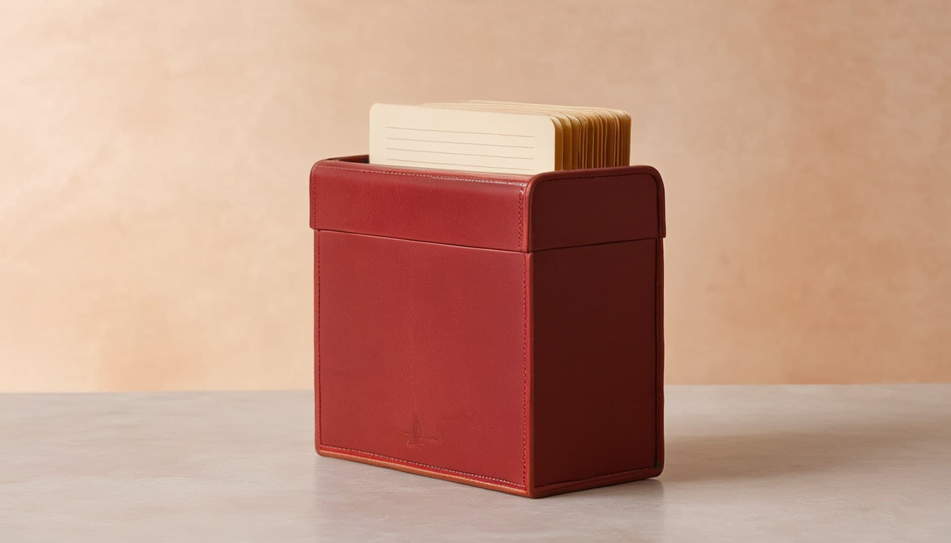 An open burgundy leather index card file box holding cream ruled cards on a pale studio surface, a physical metaphor for n8n Data Tables as small native storage next to a full database